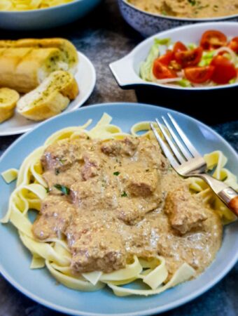A plate of tagliatelle covered with chicken in a creamy garlic and mushroom sauce.