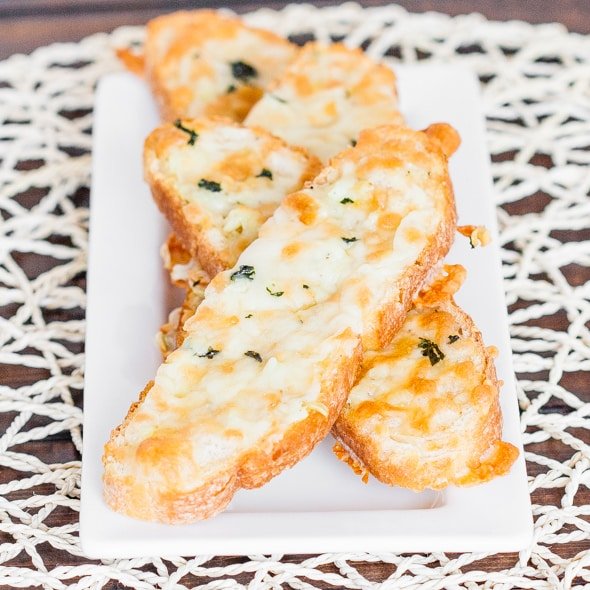 4 pieces of cheesy garlic bread arranged on a plate.