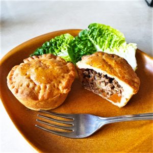 Two mini beef and onion pies on a plate.