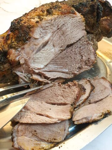 A roasted leg of lamb being carved into slices.