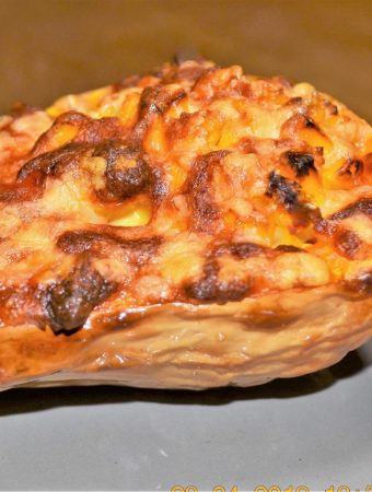 Half a baked butternut, stuffed with cheese and corn, on a plate.