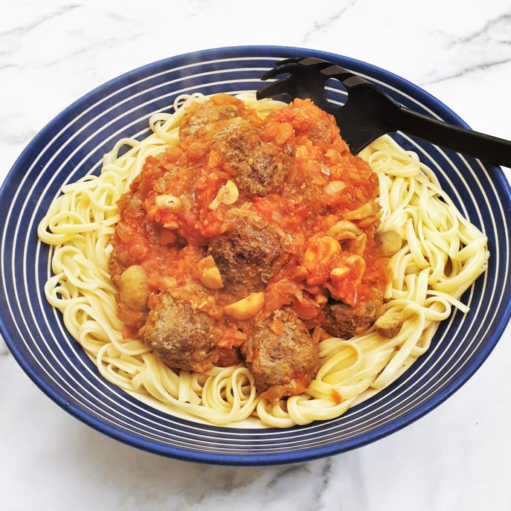 Spicy meatballs in homemade tomato sauce on a bed of spaghetti.