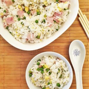 A bowl of egg fried rice next to the serving dish.