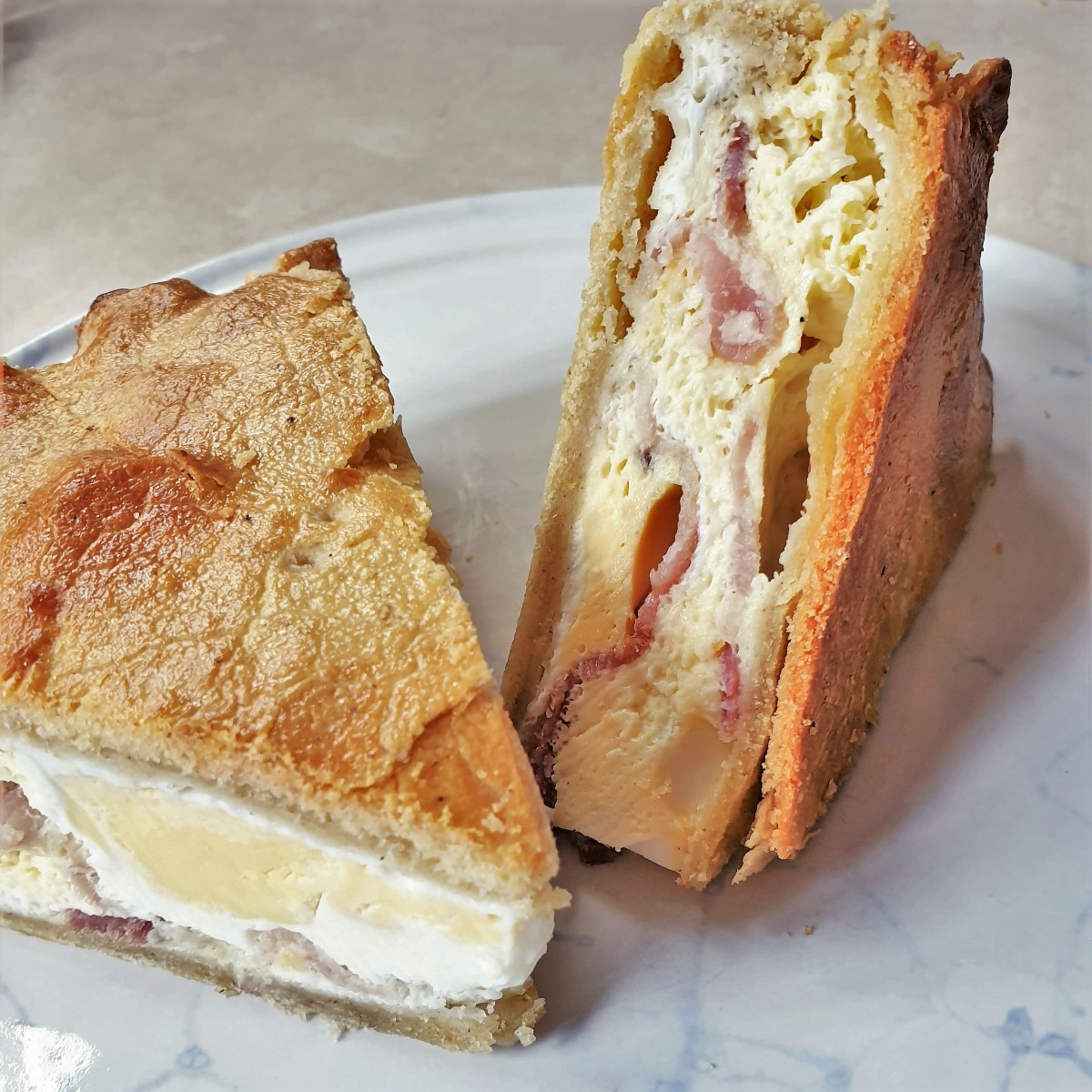 Two slices of bacon and egg pie on a plate.