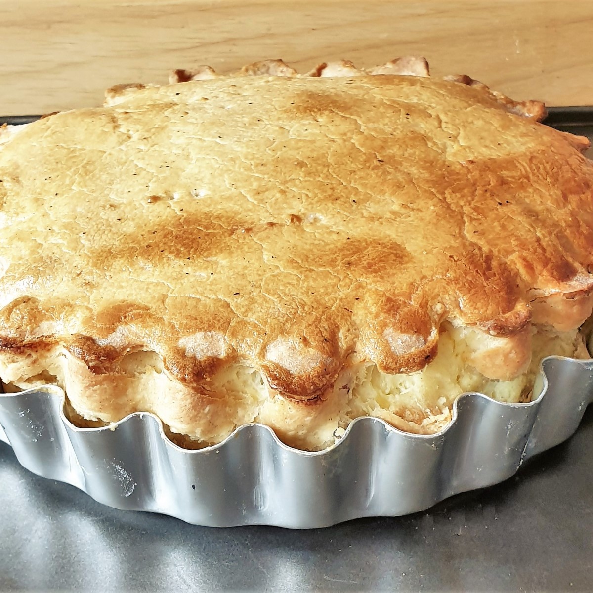 A bacon and egg pie in a baking dish from the side, showing the pastry rise.