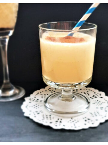 A glass of dom pedro cocktail with a blue and white striped straw.