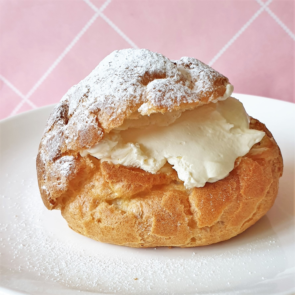 A cream puff filled with cream on a plate.