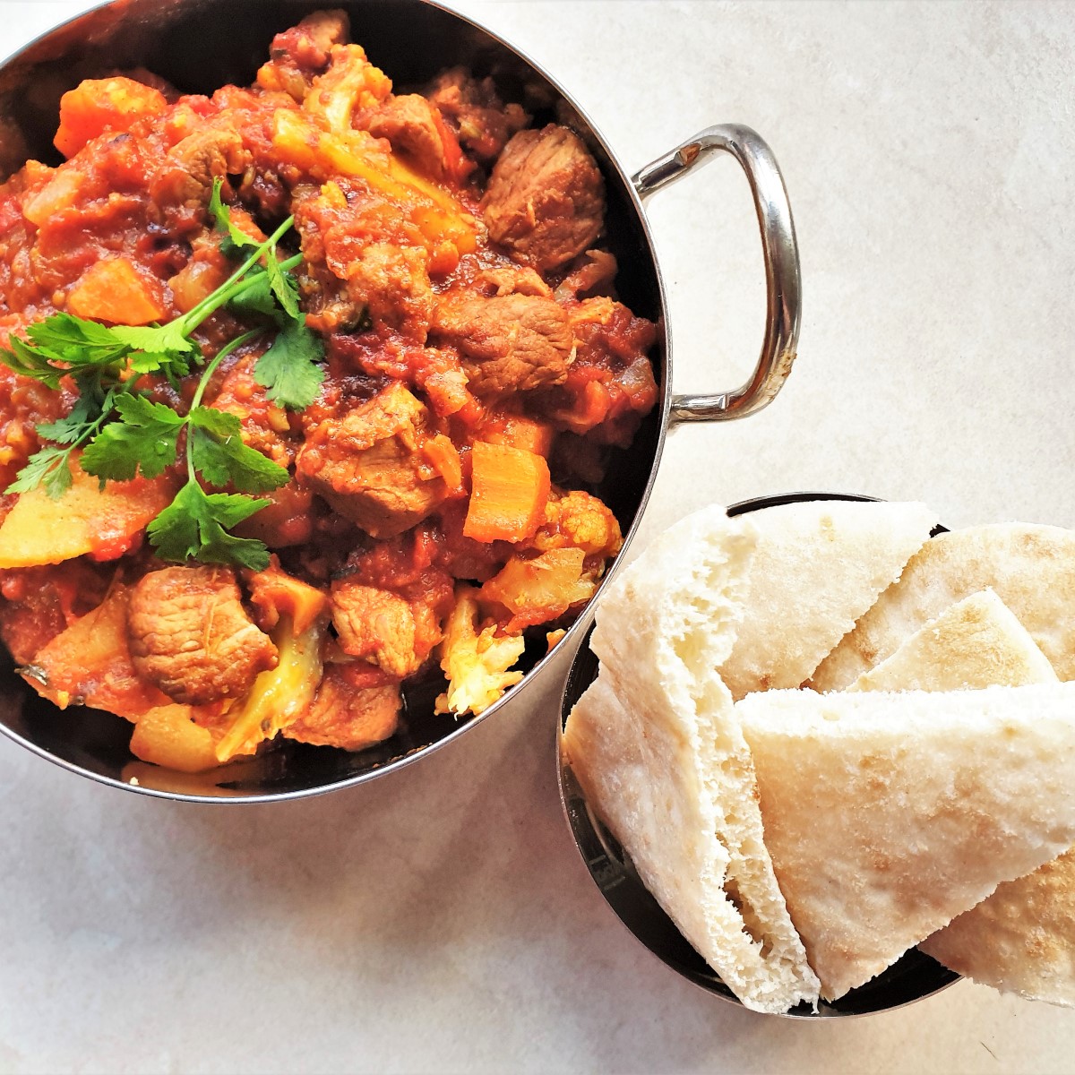 A balti dish of lamb curry alongside a slices of naan bread