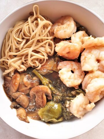 A bowl of honey garlic shrimp with saucy steamed vegetables and noodles.