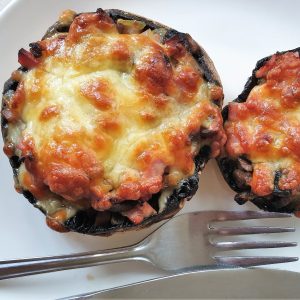 A large cheese covered stuffed mushroom on a plate.