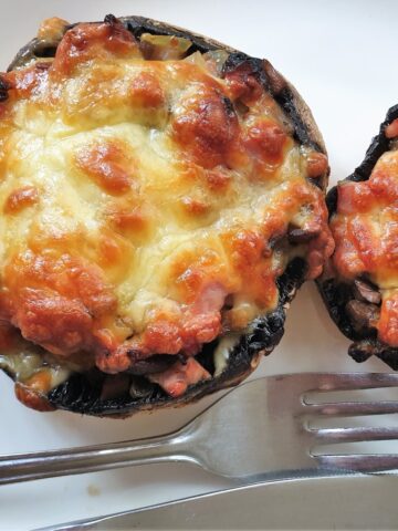 A large cheese covered stuffed mushroom on a plate.