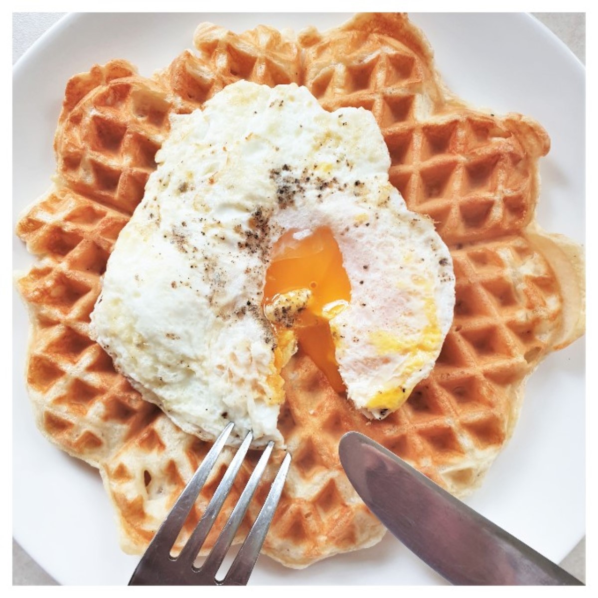 A fried egg with a runny yolk on a waffle.