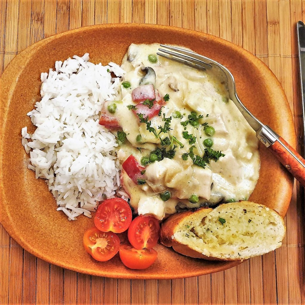 Chicken a la king on a plate with rice.