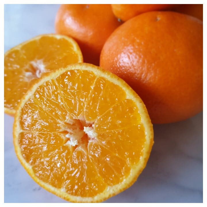 A pile of oranges, one cut in half to show how juicy they are.