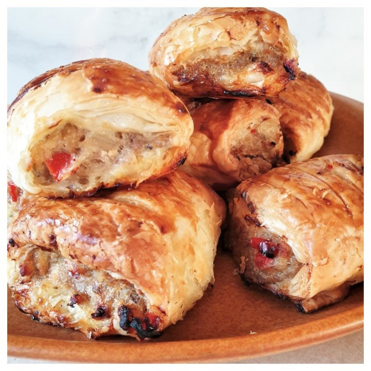 A pile of pork and apple sausage rolls on a plate.