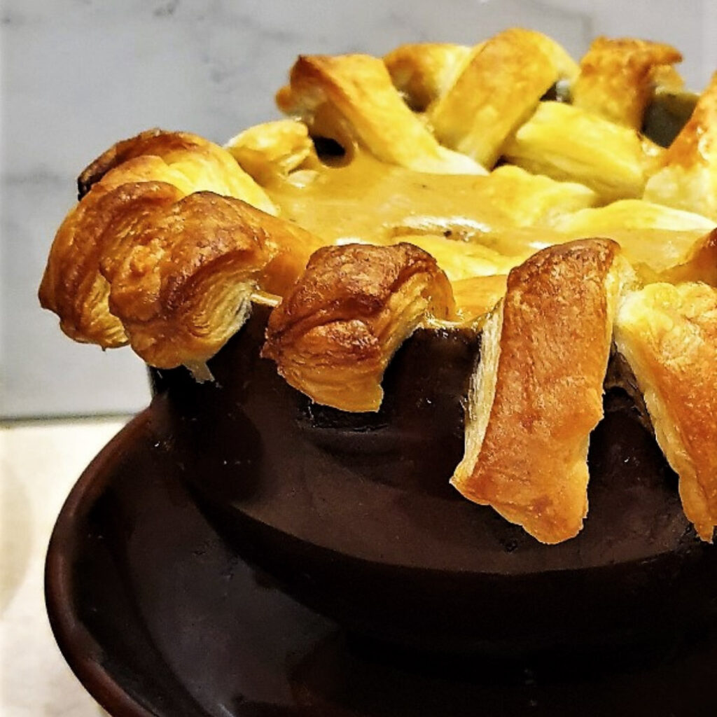 A beef pot pie topped with a lattice of puff pastry.