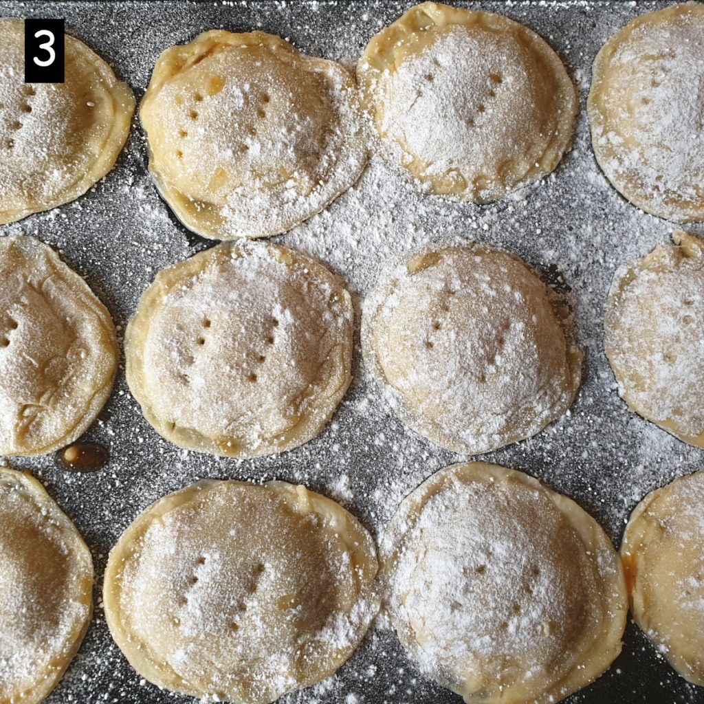 A tray of Christmas mince pies sprinkled with icing sugar.