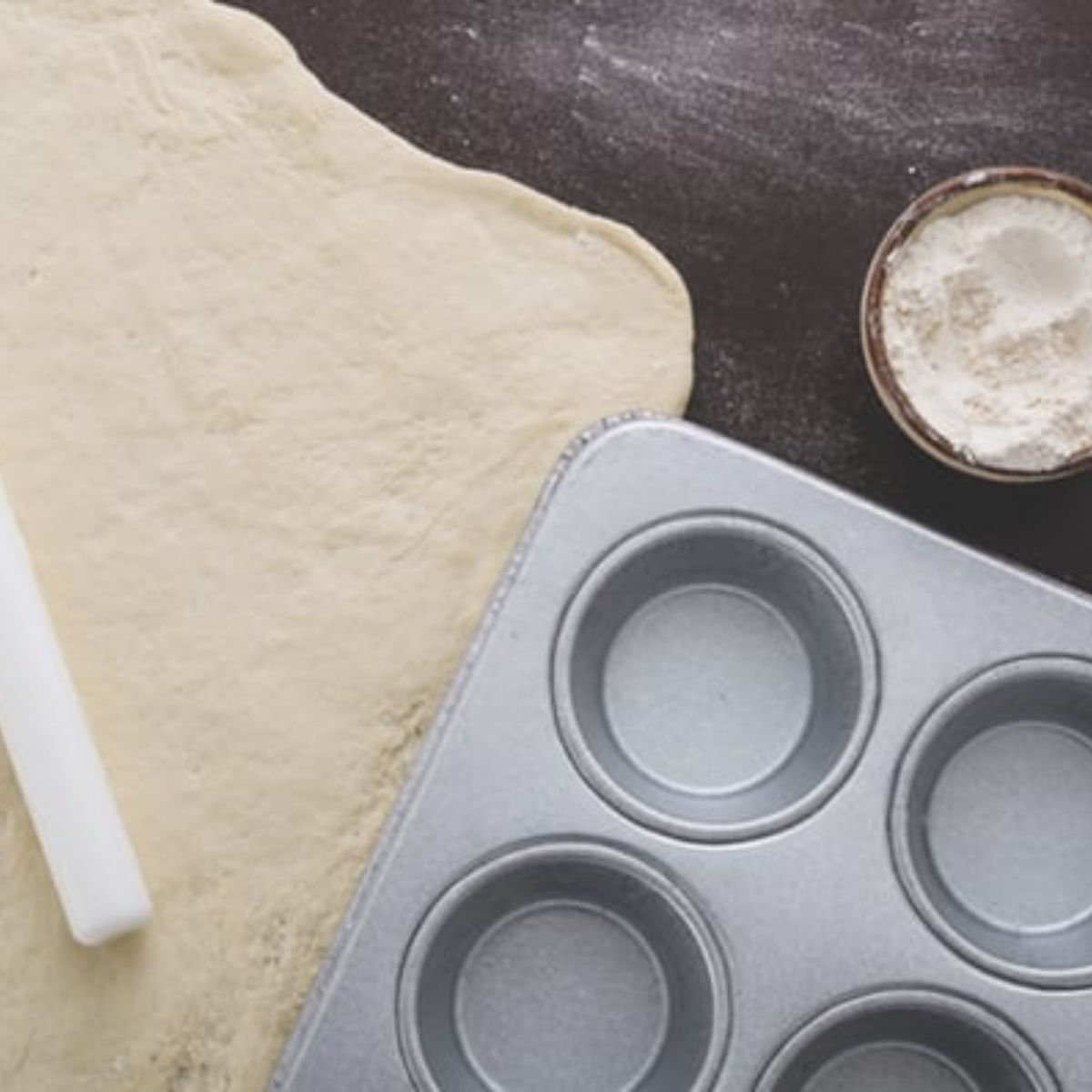 A sheet of rolled pastry with a muffin tin.