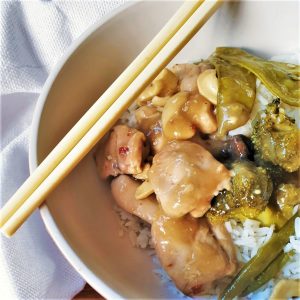 A dish of cashew nut chicken in a bowl with chopsticks.