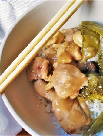 A dish of cashew nut chicken in a bowl with chopsticks.