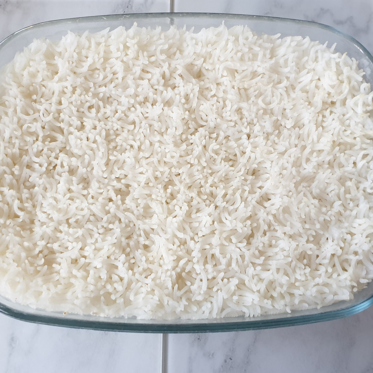 A baking dish containing cooked fluffy white rice.