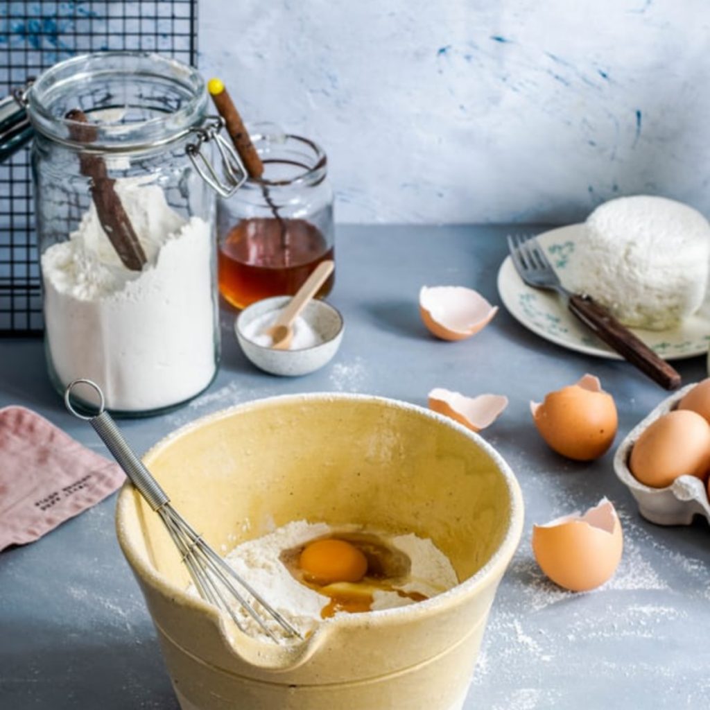 A cake being mixed with jars in the background.