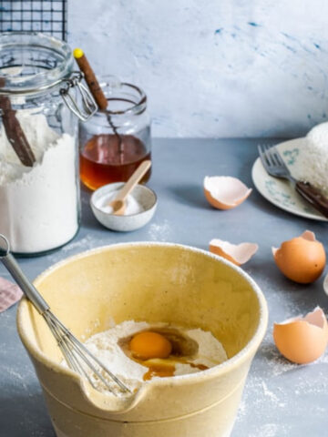 A cake being mixed with jars in the background.