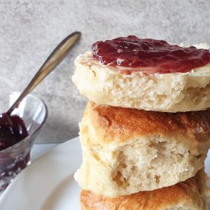 A pile of lemonade scones with the top one spread with jam.