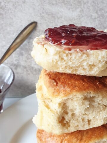 A pile of lemonade scones with the top one spread with jam.