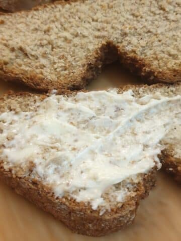 Two slices of wholemeal soda bread, one of them plain and the other spread with butter.