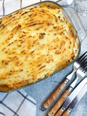 A dish of cottage pie covered with cheesy mashed potatoes.