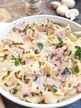 Ham and mushroom tagliatelle in a dish on a table.