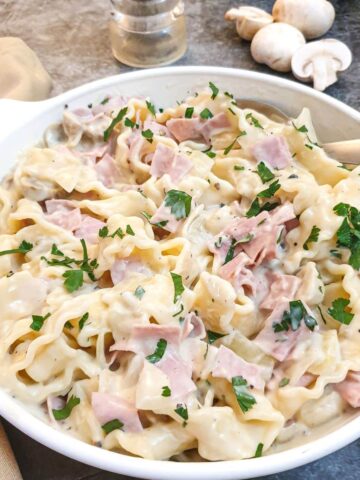 Ham and mushroom tagliatelle in a dish on a table.