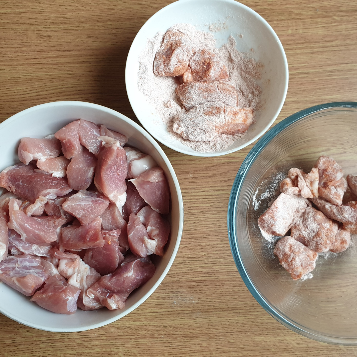 Pork pieces being coated with flour and paprika.