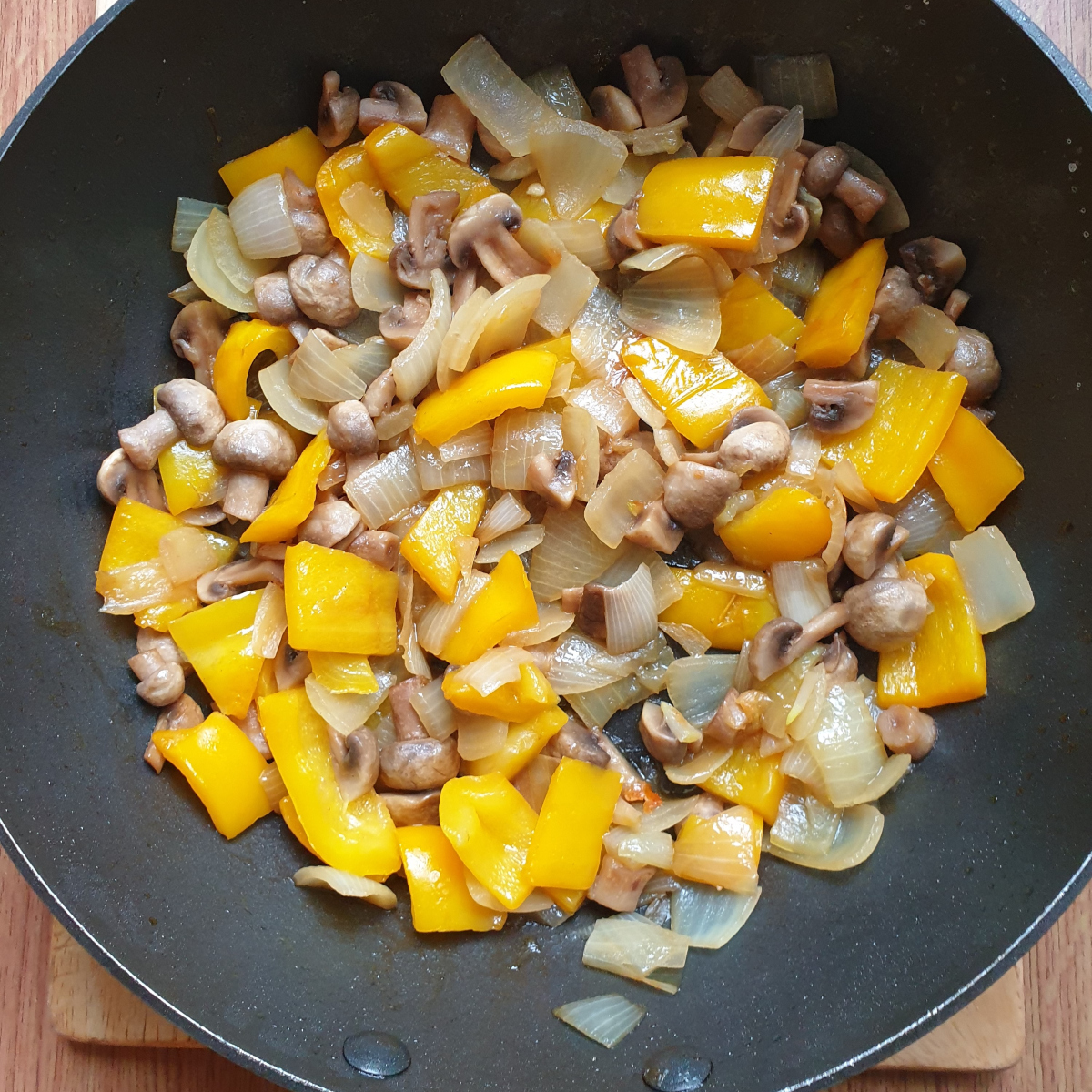 Mushrooms, yellow pepper and onions in a frying pan.