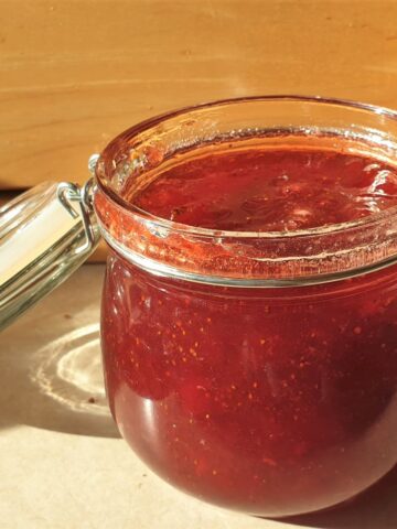 An open jar of homemade strawberry jam.