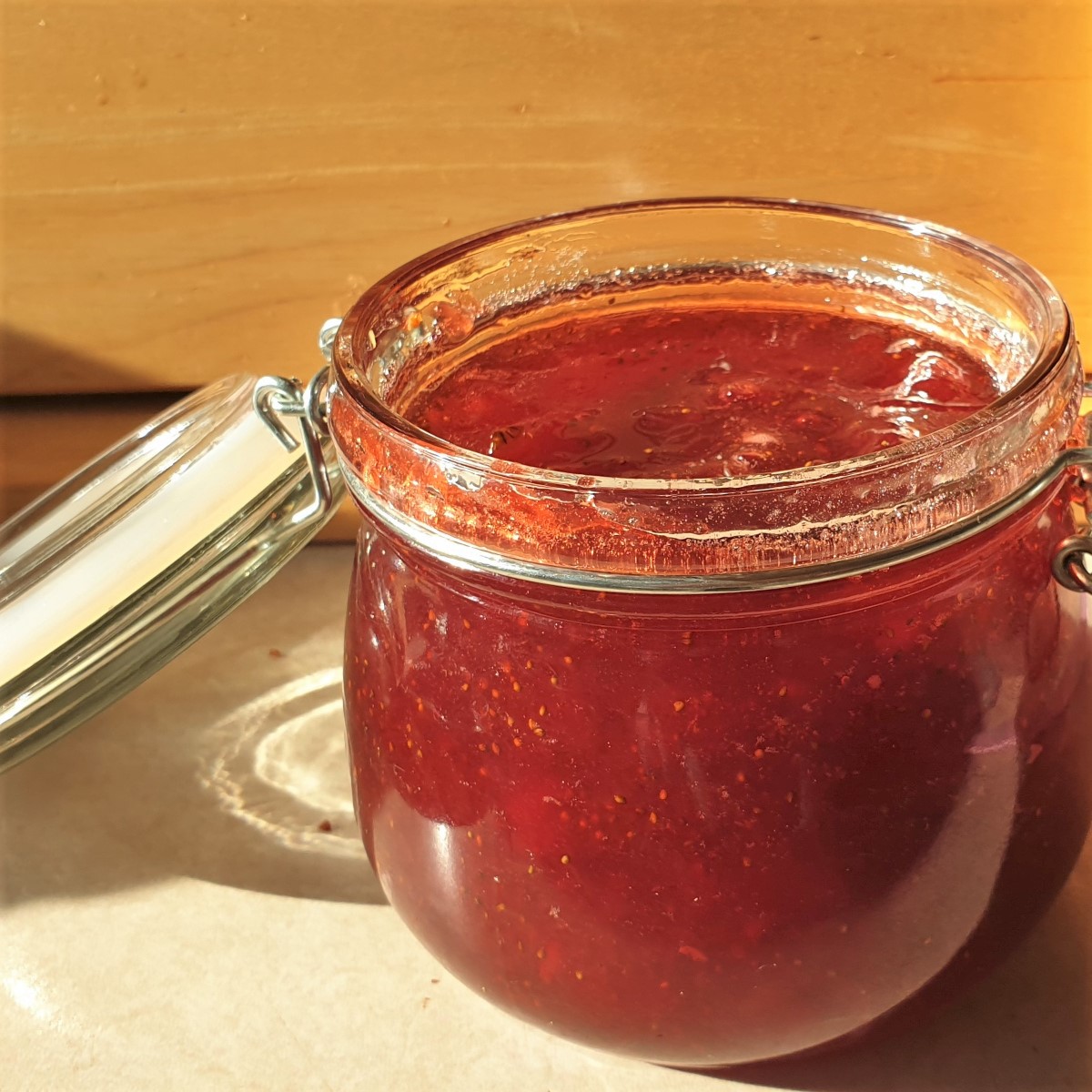 An open jar of homemade strawberry jam.