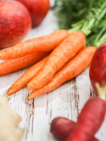 A bunch of fresh carrots with apples.