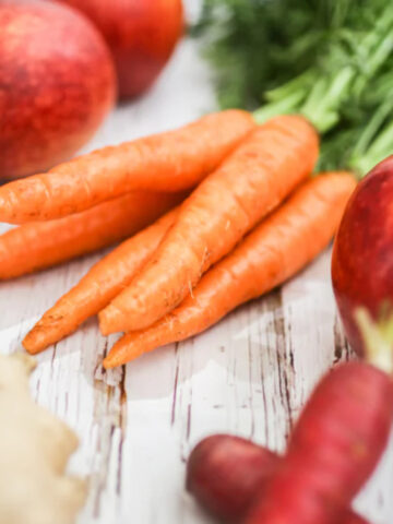 A bunch of fresh carrots with apples.