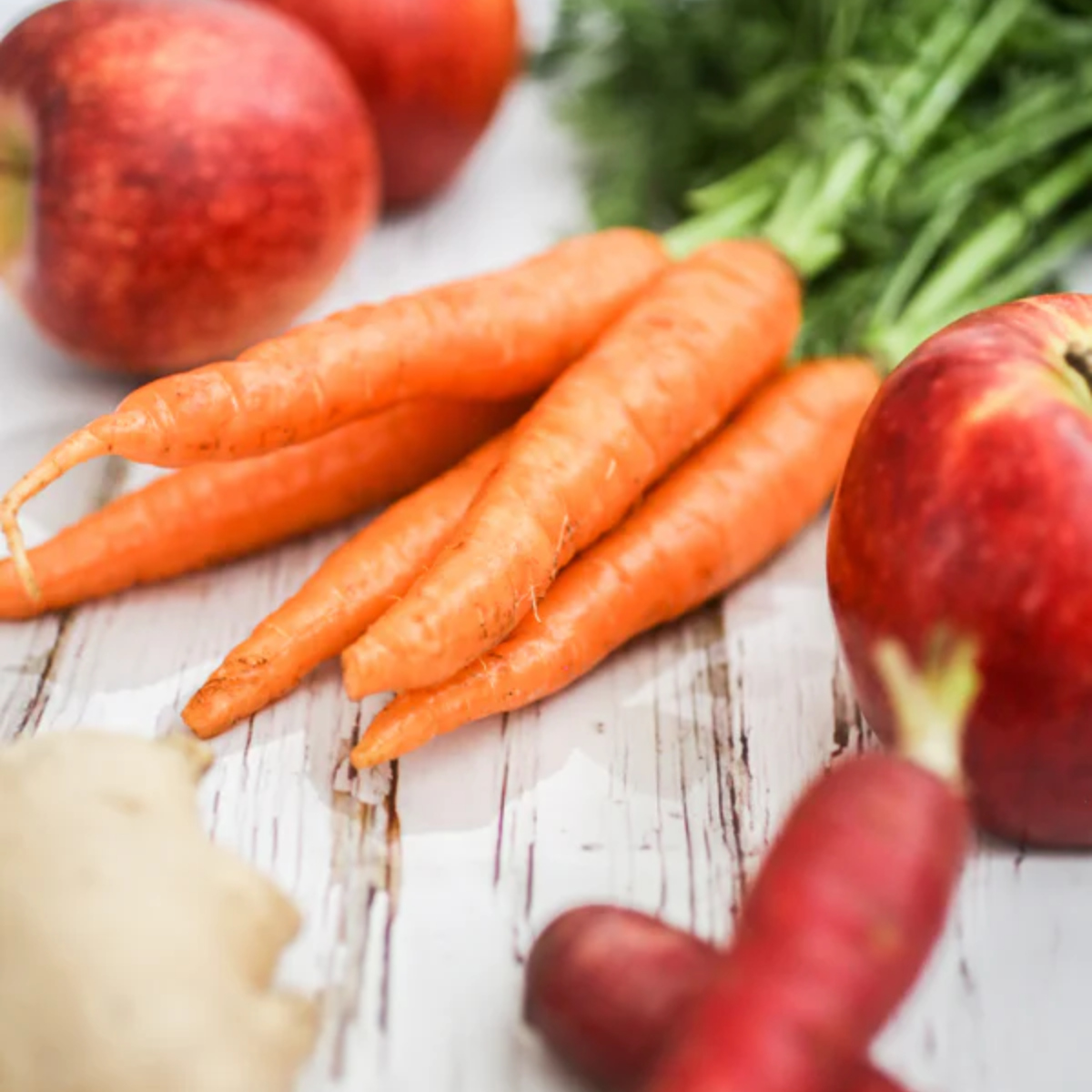 A bunch of fresh carrots with apples.