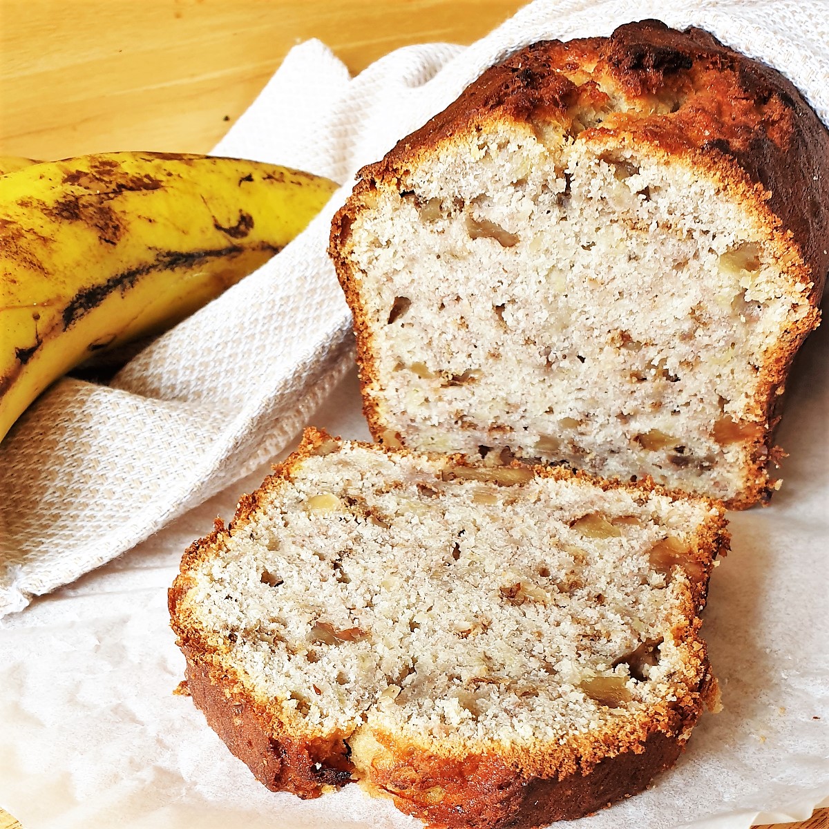 A banana walnut loaf with a slice in front of it, showing the texture.