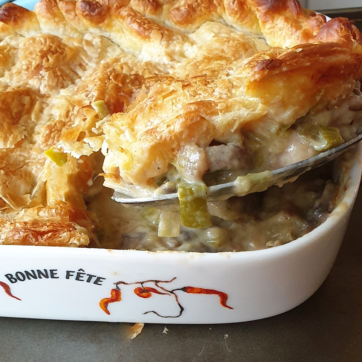 A slice of chicken leek and mushroom pie being lifted from a dish.