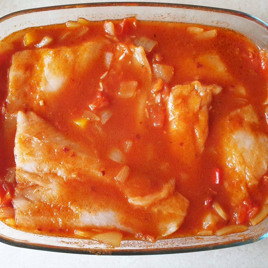 Fish fillets in a dish of sauce.