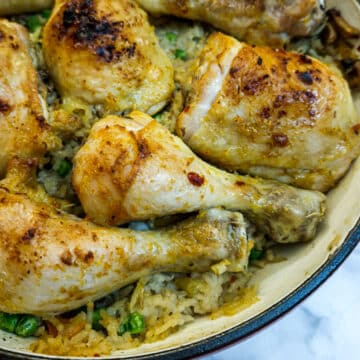 Close up of cooked garlic chicken on a bed of oven-baked garlic rice with peas mixed in.