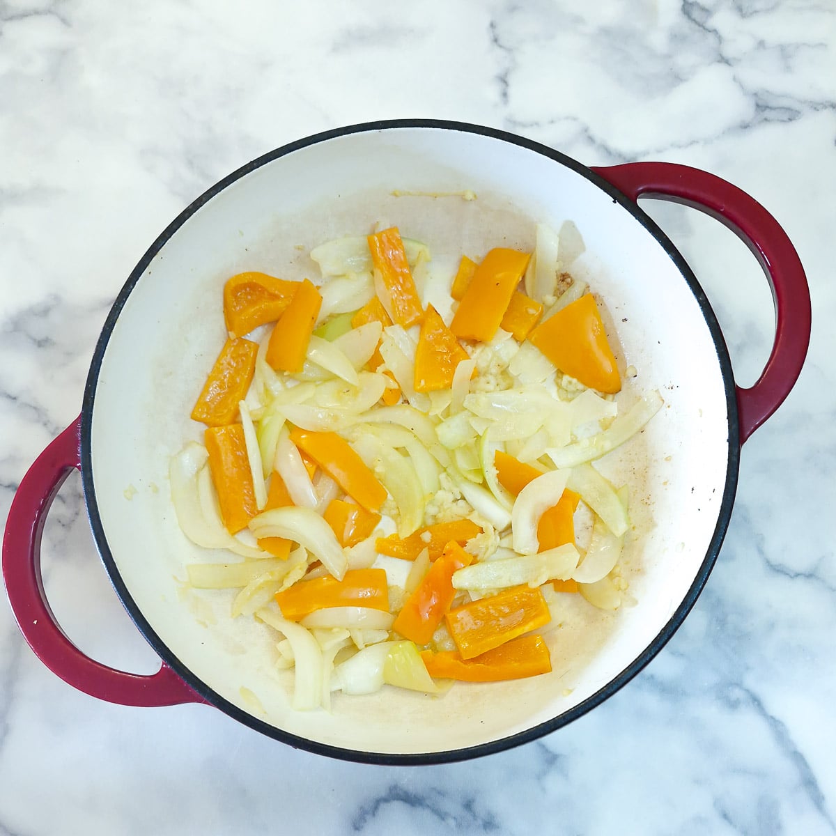 Onions and capsicum softening in butter n a dutch oven.