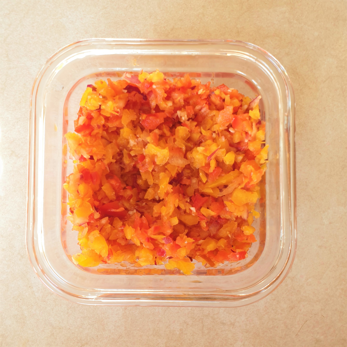 A dish of chopped red and yellow peppers and red onion.