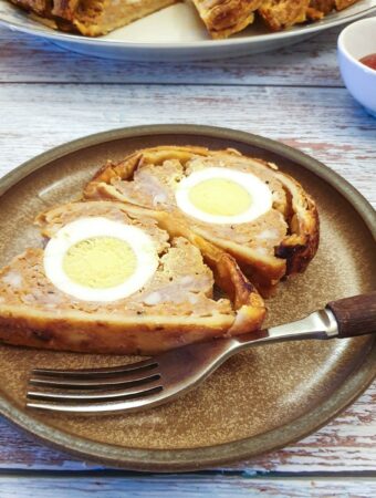 Two slices of sausage and egg picnic roll on a plate showing the egg on the inside.