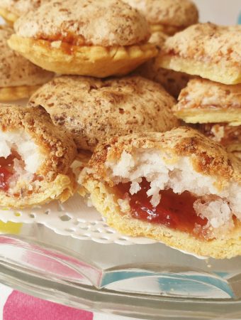 Close up of the inside of a coconut meringue jam tart on a plate.