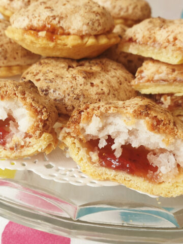Close up of the inside of a coconut meringue jam tart on a plate.