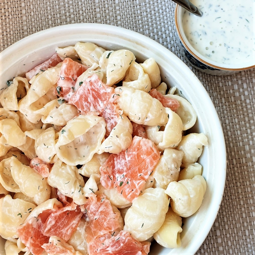 A bowl of smoked salmon pasta salad with a dish of homemade ranch dressing.